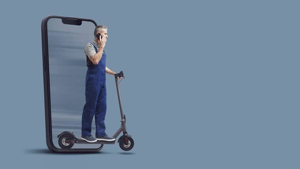 Professional fast repairman riding an electric scooter and talking with a smartphone, he is coming out from a smartphone screen, express repair service concept, blank copy space - Foto, Imagen