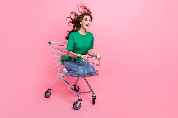 Photo of overjoyed lady buyer sit cart look empty space fast ride buy trendy clothes new purchase low price isolated pink color background. - Foto, afbeelding