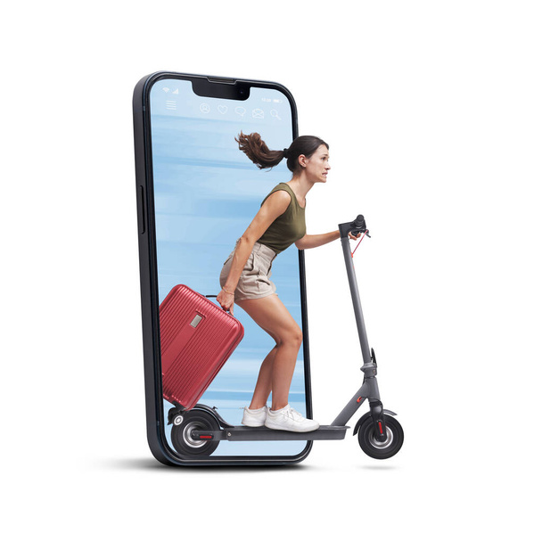 Traveller woman holding a trolley bag and riding an eco-friendly electric scooter, she is coming out from a smartphone screen, isolated on white background - Foto, afbeelding
