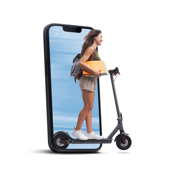 Happy young student riding an eco-friendly electric scooter, she is coming out from a smartphone screen, sustainable mobility concept - Φωτογραφία, εικόνα