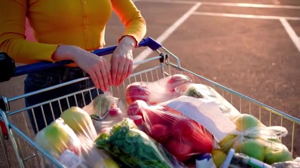 Ételes kocsi közelkép. Egy bevásárlókocsival teli kocsi megy a szupermarketbe. Kiváló minőségű 4k felvételek - Felvétel, videó