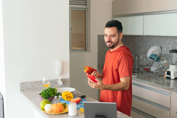 Νεαρός χρησιμοποιεί smartphone στην κουζίνα - Φωτογραφία, εικόνα