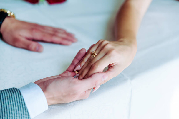 結婚指輪を持つ男と女の写真。若い夫婦が手を握って結婚式の日。新婚夫婦の手と結婚指輪. - 写真・画像