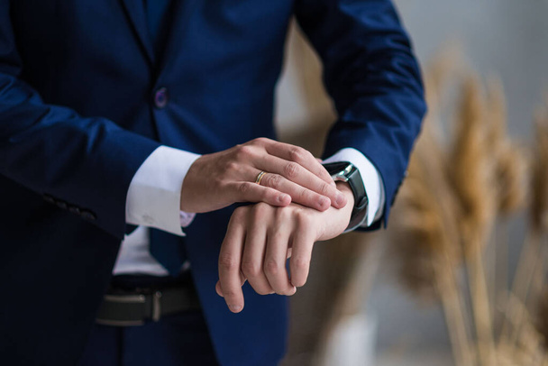 επιχειρηματίας ελέγχει το χρόνο στο ρολόι του καρπού του, άνθρωπος βάζοντας το ρολόι στο χέρι, γαμπρός ετοιμάζεται το πρωί πριν από την τελετή του γάμου - Φωτογραφία, εικόνα