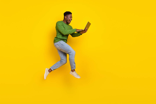 Full length body size view of attractive cheery guy jumping using laptop web order buy isolated over vivid yellow color background. - Фото, изображение