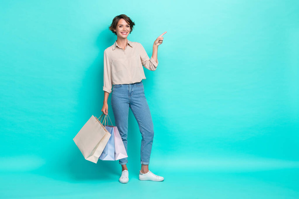 Full length photo of positive customer stylish clothes arm direct empty space offer recommend low price isolated on cyan color background. - Fotografie, Obrázek