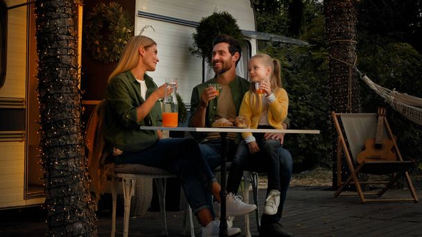 Kavkazská rodina sedí v lese kempování dovolená venku v blízkosti van jíst oběd mají piknik s croissants a pomerančový džus matka otec a dítě dívka pití čerstvé mluvení osvěžující s pitím - Fotografie, Obrázek