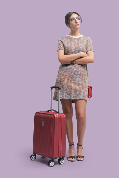 Elegant young woman traveling alone with a trolley case, tourism and travel concept - Foto, afbeelding