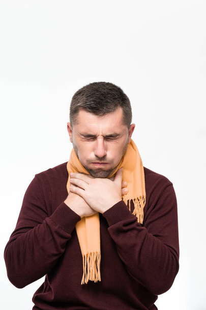 A man suffers from a sore throat, a man wrapped his throat with a scarf, portrait on a white background, severe sore throat. - Photo, image