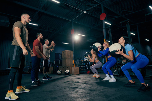Group training. Sportive youth, muscled men and women in sports uniform workout at sport gym, indoors. Sport, active lifestyle, health, youth concept. Concept of health, sportive lifestyle, fitness - Фото, изображение