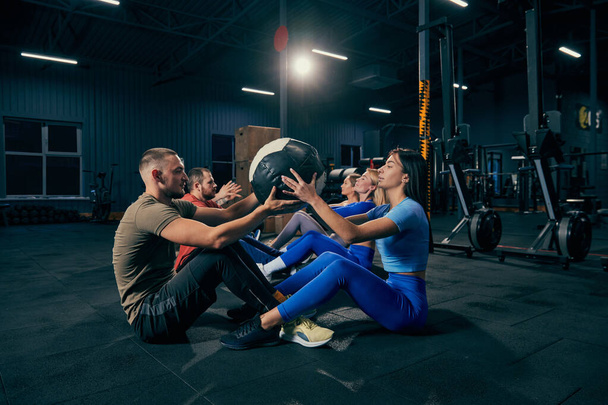 Group training. Sportive youth, muscled men and women in sports uniform workout at sport gym, indoors. Sport, active lifestyle, health, youth concept. Concept of health, sportive lifestyle, fitness - Фото, изображение