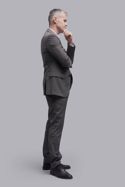 Corporate businessman standing and waiting, side view, full-length portrait - Valokuva, kuva