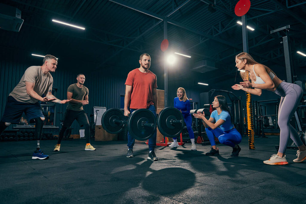 Group of young people doing sports, workout at sport gym, indoors. Sport, active lifestyle, health, youth concept. Concept of health, sportive lifestyle, fitness, beauty, body care, diet - Photo, Image