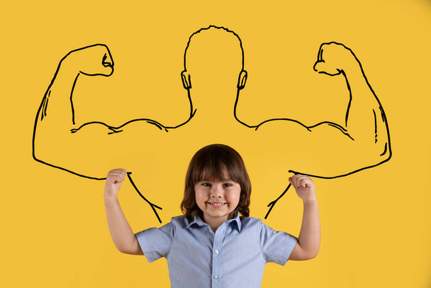 Dromen om bodybuilder te worden. Schattig jongetje demonstrerend biceps, staand over gespierde sporter silhouet, glimlachend naar camera, oranje studio achtergrond - Foto, afbeelding