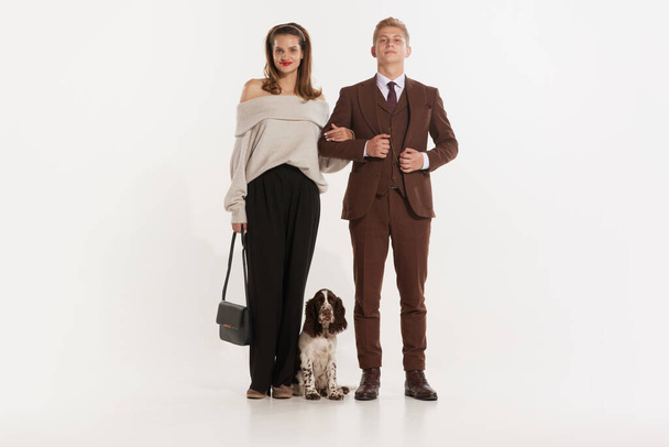 Full length photo of two elegant lovely partners posing isolated on white studio background with dog. Young retro man and woman. Concept of senior people, family, love, vintage, couple, lifestyle - Фото, зображення