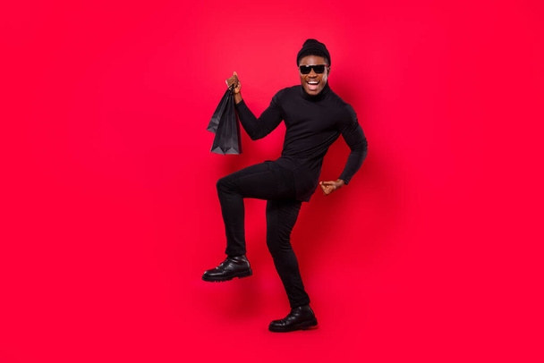 Full length body size view of attractive cheerful trendy guy buying gifts dancing having fun isolated over bright red color background. - Zdjęcie, obraz
