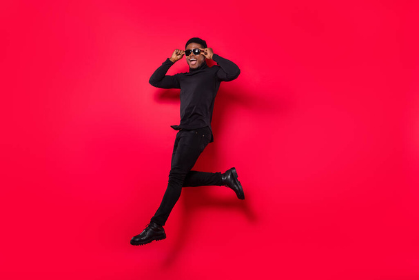 Full length body size view of handsome trendy cheerful guy jumping running touching specs isolated over bright red color background. - Fotografie, Obrázek