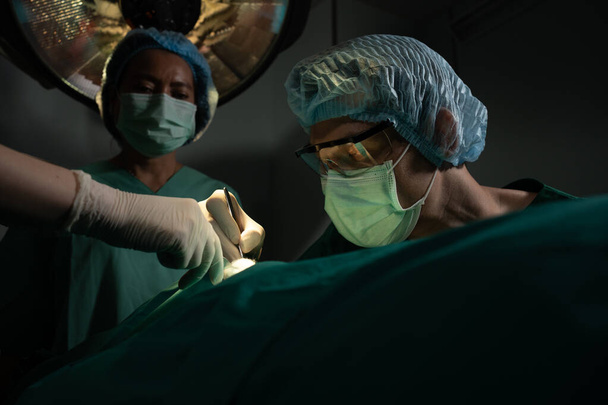 Equipo de cirujanos profesionales asiáticos que realiza cirugía en el quirófano, cirujano, asistentes y enfermeras que realizan cirugía en un paciente, el cáncer de atención médica y el concepto de tratamiento de enfermedades - Foto, imagen