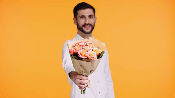 happy bearded man holding bouquet of flowers isolated on yellow  - Foto, afbeelding