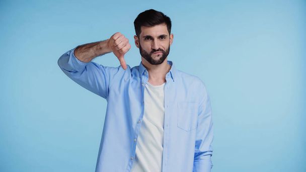 displeased bearded man in shirt showing thumb down isolated on blue - Foto, imagen