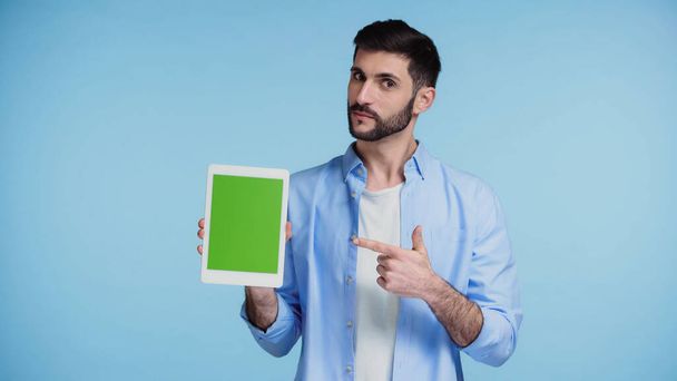 bearded man pointing with finger at digital tablet with green screen isolated on blue  - Foto, imagen