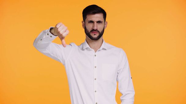 dissatisfied man in white shirt showing thumb down isolated on yellow - Photo, Image
