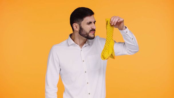 displeased man in white shirt holding stinky socks isolated on yellow  - Photo, Image