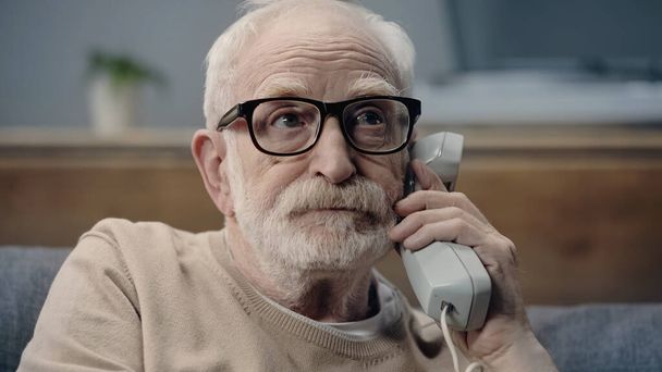 Hombre mayor con demencia sosteniendo auriculares de teléfono vintage  - Foto, Imagen