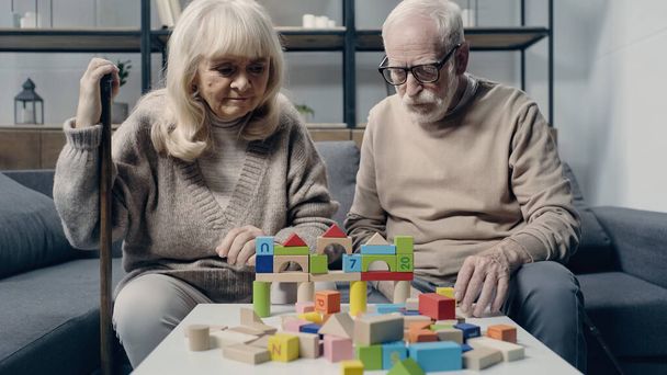 Senior couple with dementia playing with colorful building blocks on table  - Foto, Imagen