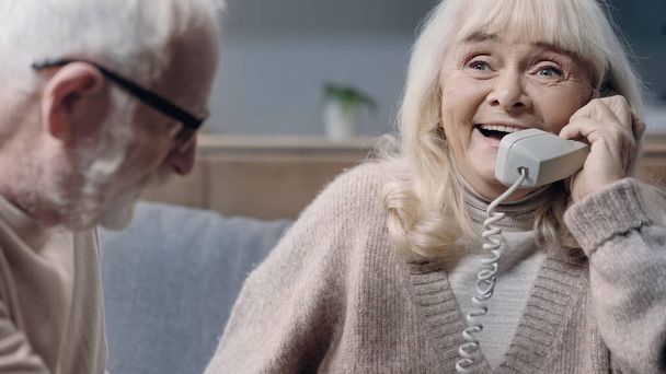 feliz mujer mayor con demencia hablando por teléfono cerca del marido  - Foto, Imagen