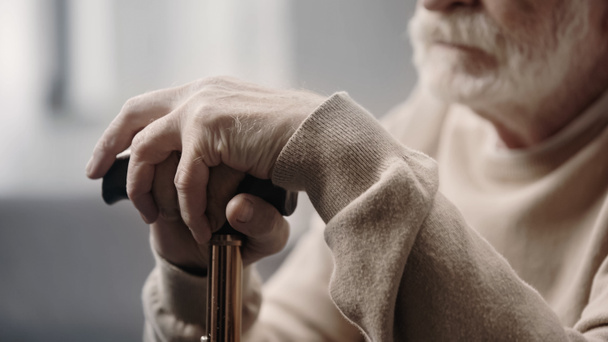обрезанный вид грустного пожилого человека со слабоумием, держащего трость  - Фото, изображение