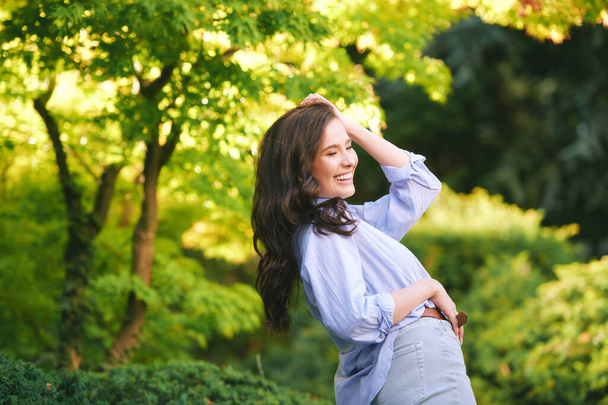 Außenporträt einer glücklichen jungen Frau, die die Umgebung im grünen Park genießt - Foto, Bild