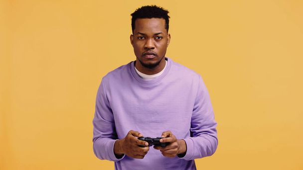 KYIV, UKRAINE - NOVEMBER 22, 2019: focused african american man playing video game isolated on yellow  - Fotoğraf, Görsel