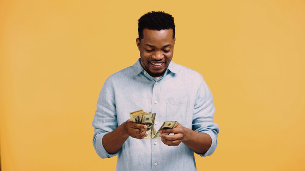 happy african american man counting dollar banknotes isolated on yellow - Foto, Imagem