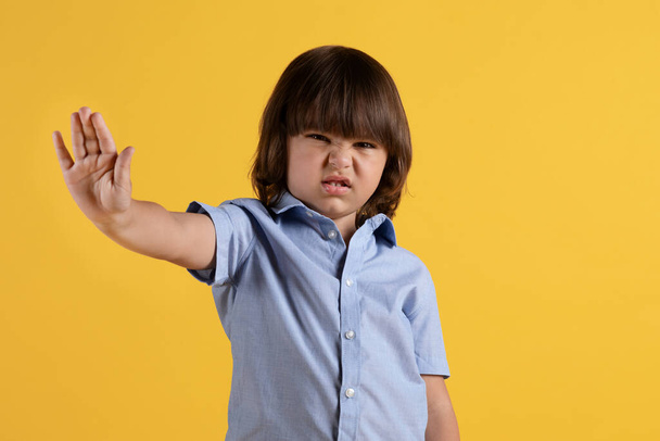 Ew, detente. Retrato de estudio de un niño disgustado mostrando el gesto STOP y la cara fruncida, sintiendo aversión, fondo naranja, espacio libre - Foto, imagen