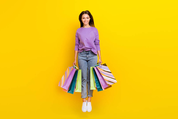 Full length photo of adorable lady wear stylish clothes two hand hold bags rejoice low price shopping isolated on yellow color background. - Foto, immagini