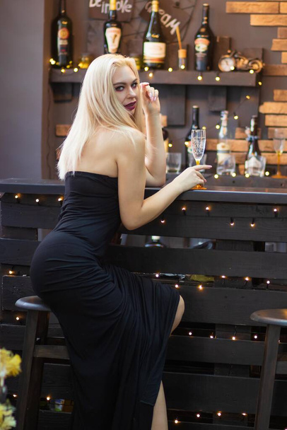Christmas image with blonde sexy woman in long black dress. Over Christmas decorate and New Year tree - Φωτογραφία, εικόνα