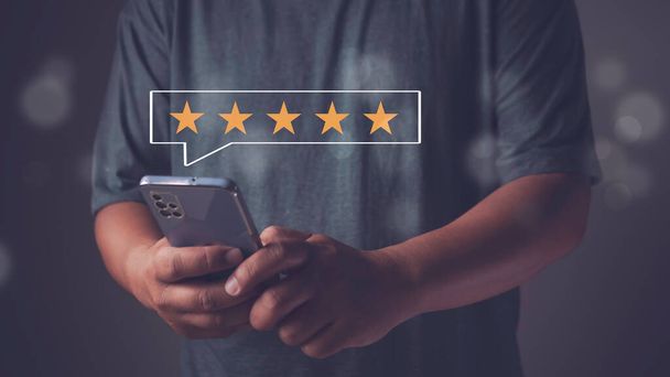 Man hand using smartphone with popup five star icon for evaluation feedback review satisfaction service, Customer give rating to service experience and business satisfaction survey - Photo, Image