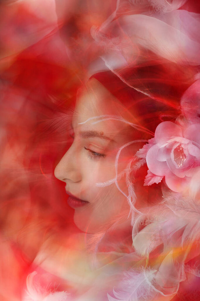 Una dama de aspecto suave está mirando a través de plumas blancas y transparentes como a través de un sueño pacífico. - Foto, imagen