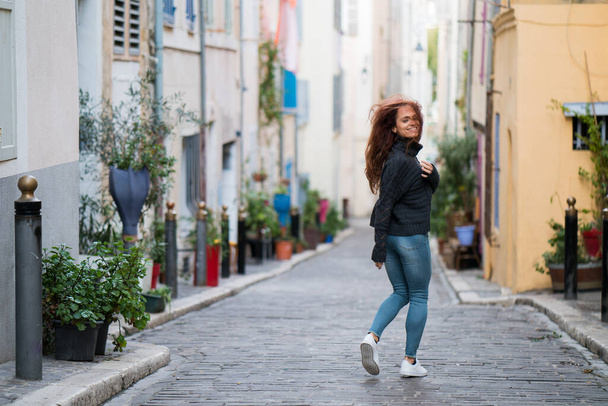 Woman running around alone in an empty street in a cheerful way. - Foto, imagen