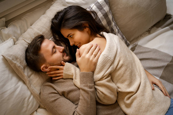 Bella giovane coppia felice rilassarsi a letto e sorridente, abbracciando - Foto, immagini
