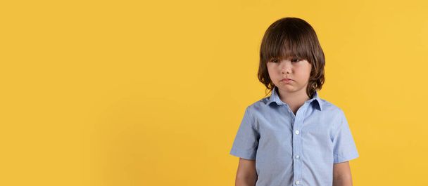 Unhappiness and kids stress. Studio portrait of little unhappy boy feeling upset, standing with crying eyes over orange background, panorama with empty space - Фото, зображення