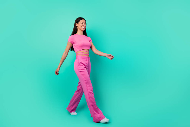 Full length profile side photo of cheerful lady travel go walk wear trend set outfit isolated cyan color background. - Фото, зображення