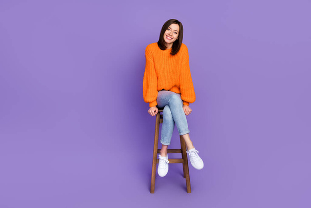 Full body photo of pretty young girl sit wooden bar chair toothy smile wear trendy orange knitwear look isolated on violet color background. - Foto, Imagen