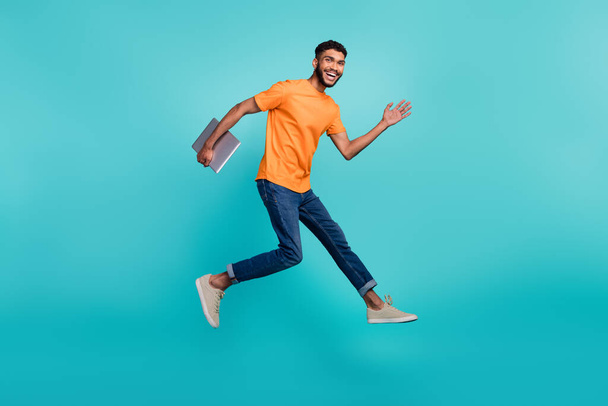 Full size profile photo of excited active man jump rush fast hold netbook isolated on aquamarine color background. - Foto, Imagen