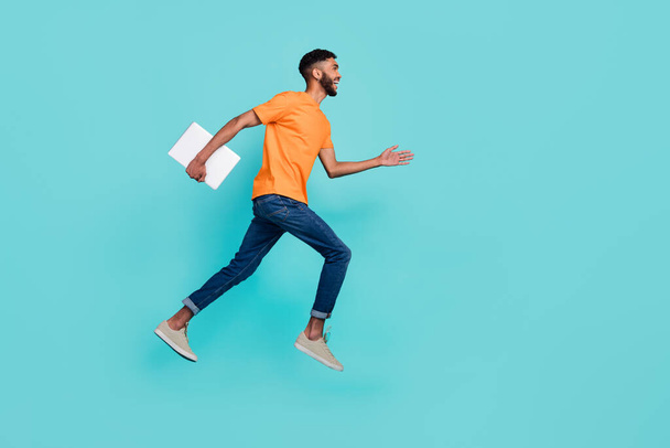 Full length profile photo of crazy guy jump hurry rush empty space hold laptop isolated on teal color background. - Zdjęcie, obraz