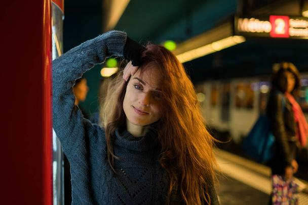 Hosszú hajú nő áll egy automata előtt, aki a metróra vár. - Fotó, kép