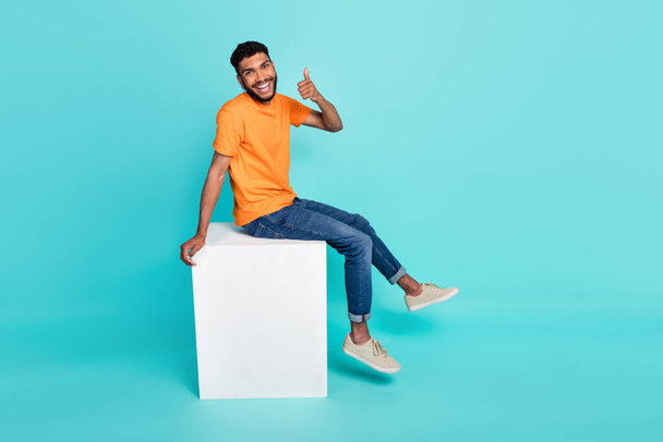 Full length photo of positive person sit podium demonstrate thumb up isolated on cyan color background. - Foto, Imagen