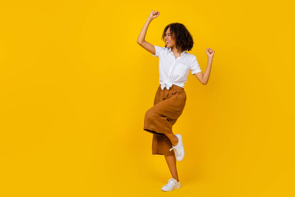 Full body photo of satisfied positive girl raise fists celebrate luck success isolated on yellow color background. - Fotó, kép