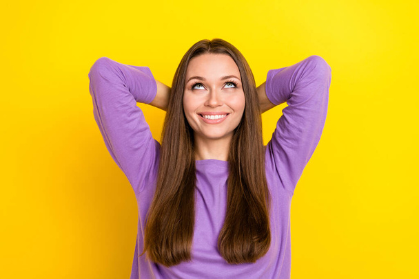 Closeup photo of young excited positive toothy smiling woman hold hands behind head looking empty space up interested isolated on bright yellow color background. - Foto, imagen